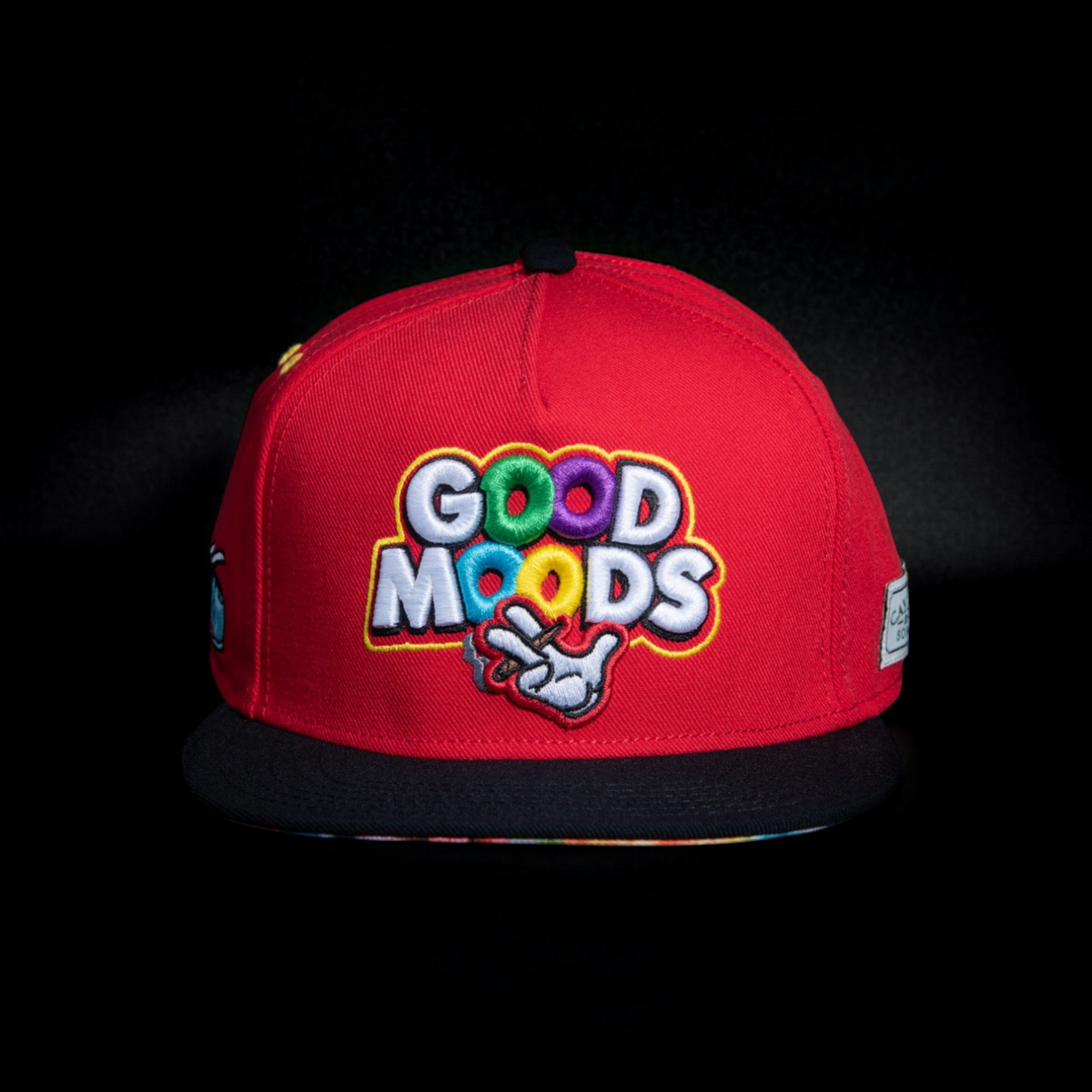 Gorra snapback roja CAYLER & SONS con bordado colorido GOOD MOODS y visera plana negra sobre fondo oscuro