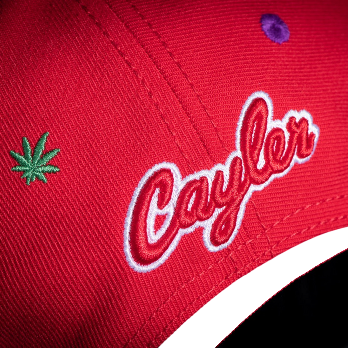 Gorra snapback roja CAYLER & SONS con bordado lateral de logo y hoja verde sobre fondo negro