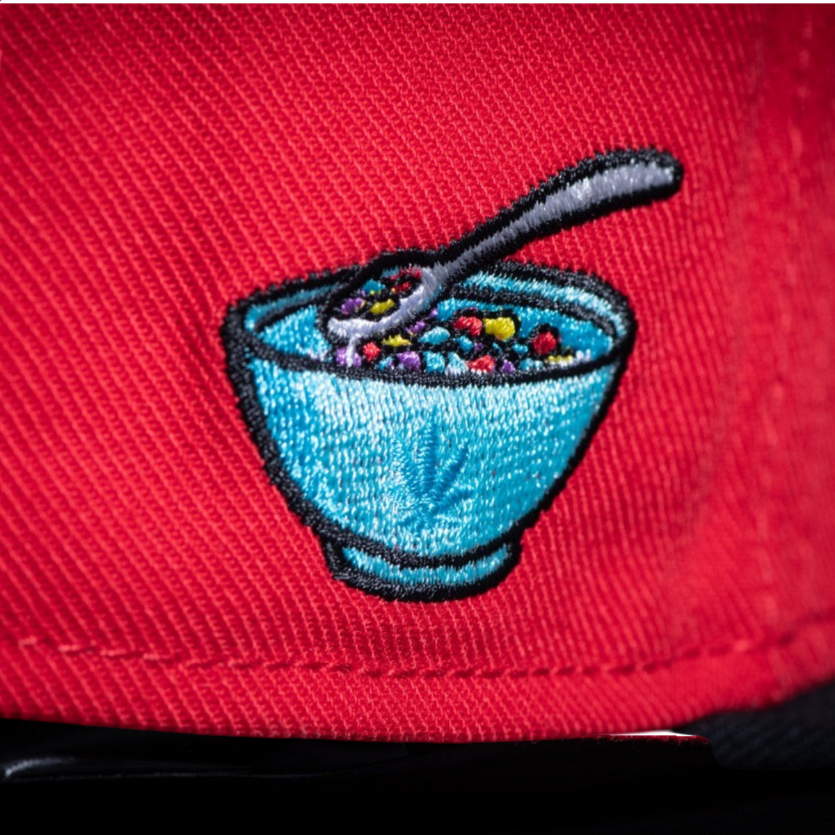 Gorra snapback roja CAYLER & SONS con bordado lateral de un tazón de cereales colorido y estilo urbano